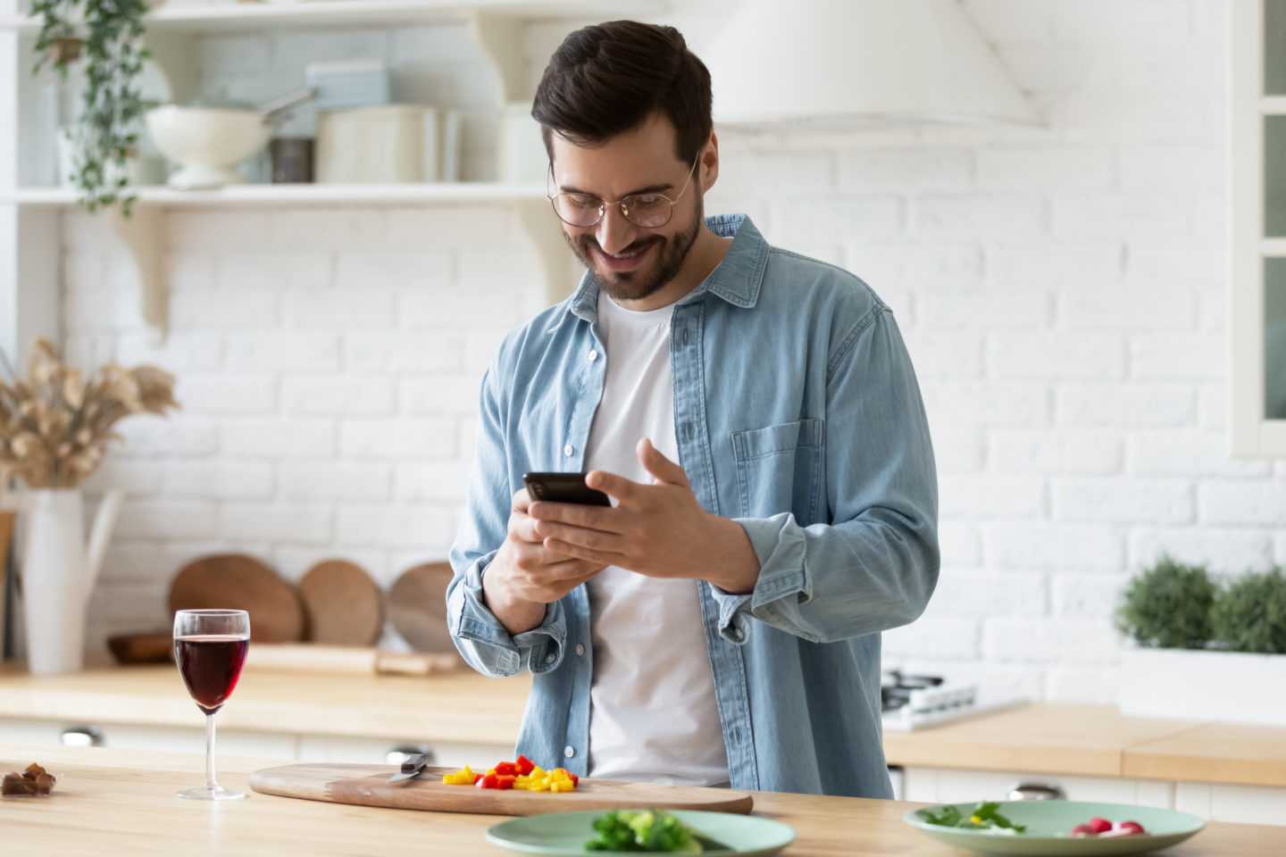 Man on smart phone cooking in kitchen