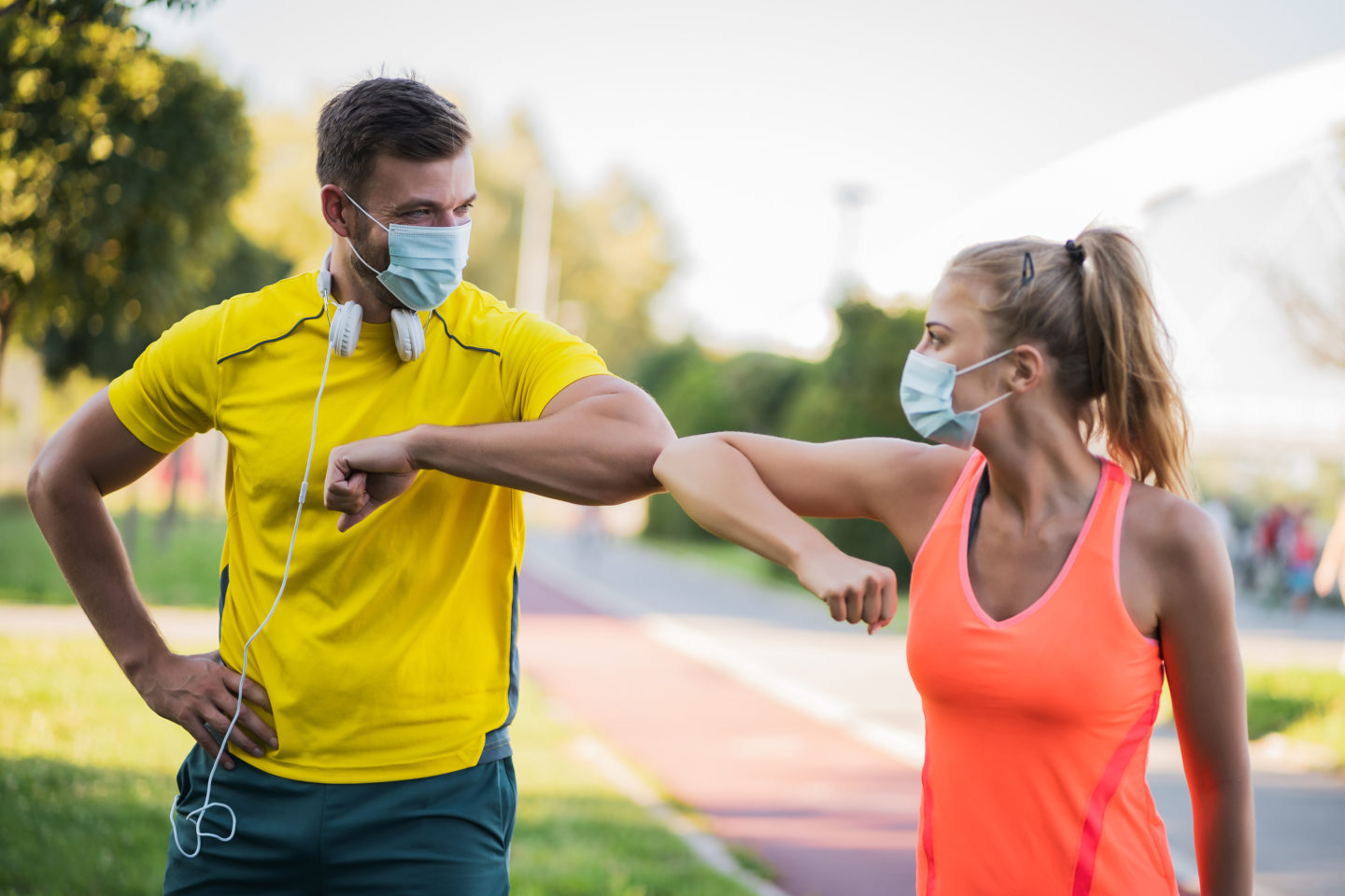 Young couple is getting ready for outdoor workout with protective masks. Covid-19 responsible behavior.
