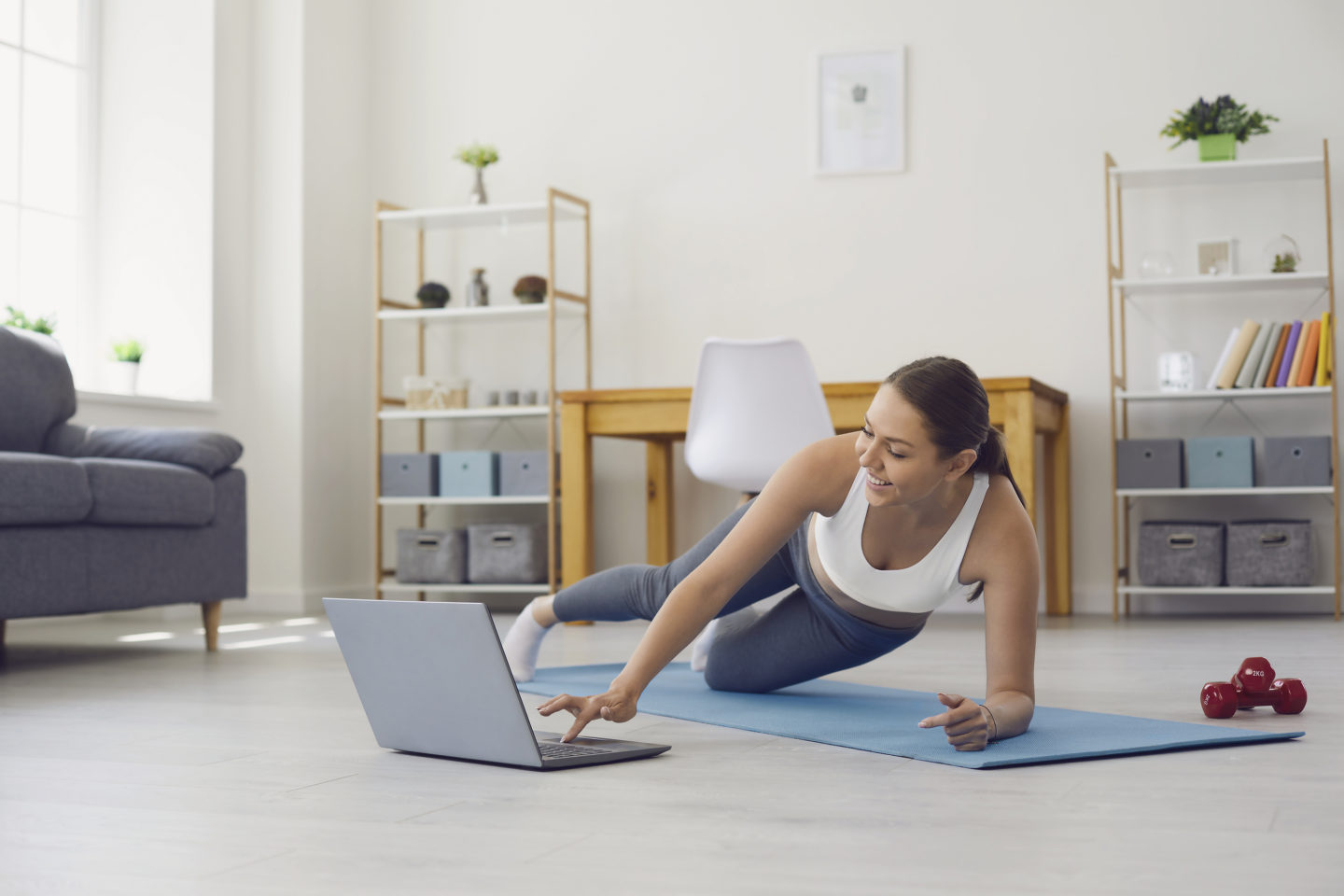 Online home fitness. Woman with laptop training to web video tutorial. Personal trainer giving yoga class via internet