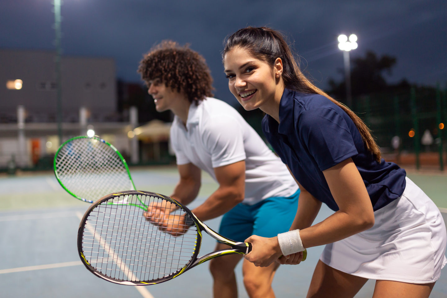 Young couple on tennis court. Handsome man and attractive woman are playing tennis.