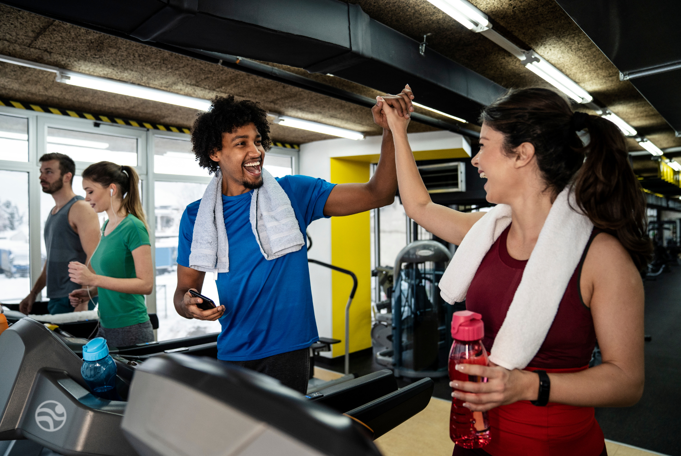 Friends hi fiving on the treadmills